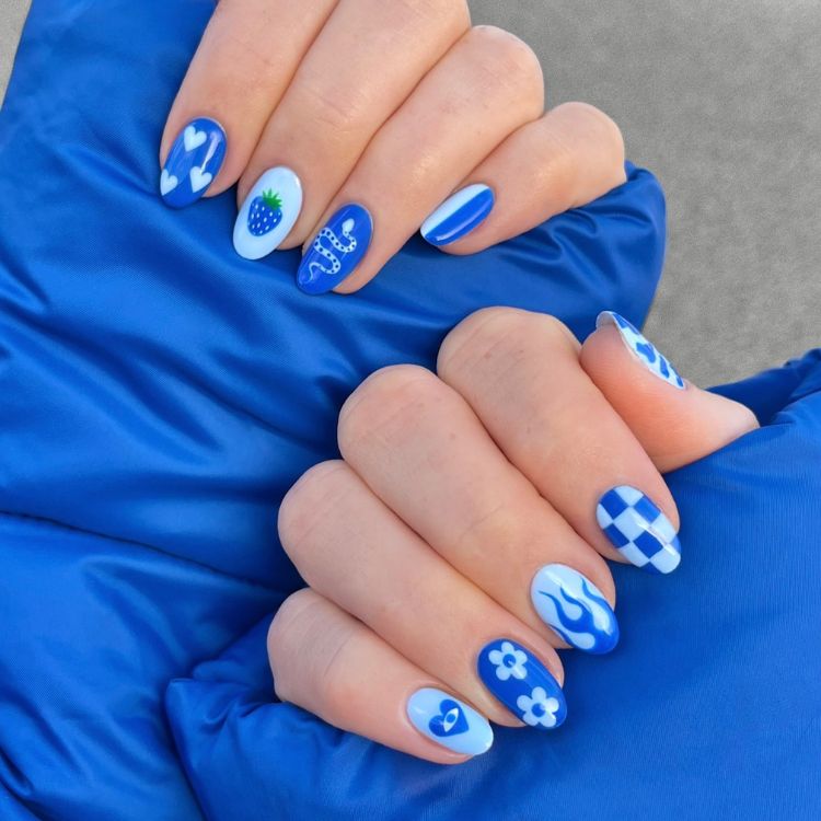 Nail art em unhas arredondadas azuis, como desenho de morango, xadrez, cobra e mais