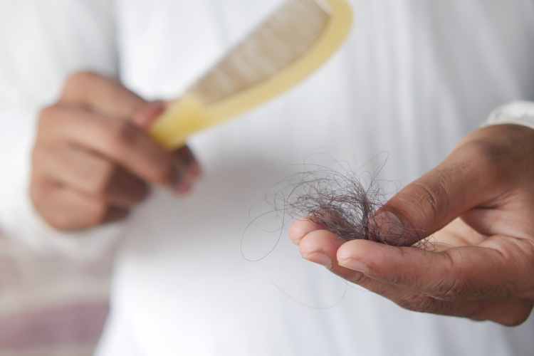 mãos segurando pente e tufo de cabelo