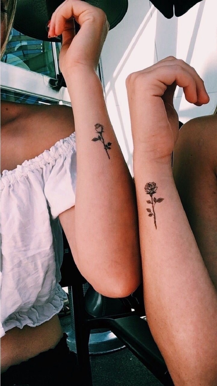 Duas pessoas com tatuagem delicada de flor no pulso 
