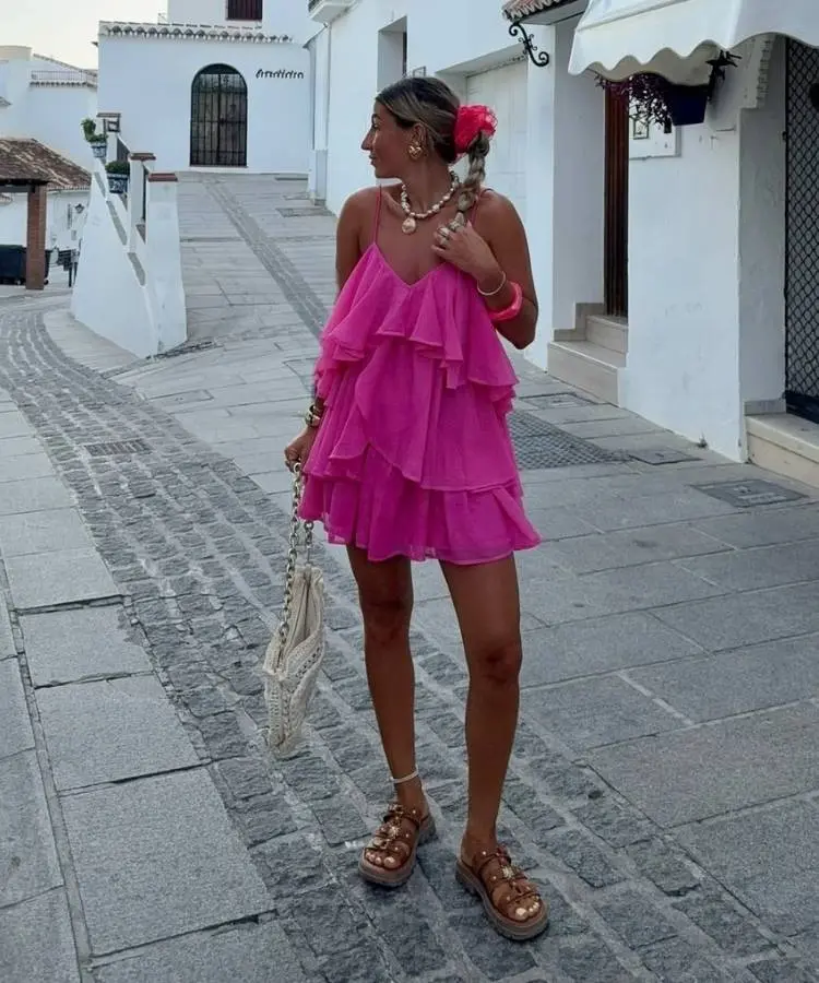 Mulher usando vestido curto de babados rosa, cor para look de Ano Novo