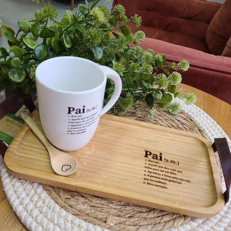 Uma caneca branca com a palavra “Pai” e definições abaixo, sobre uma bandeja de madeira com a mesma palavra e definições.