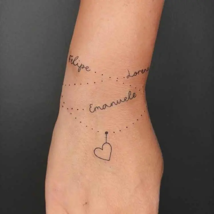 tatuagem no pulso formato de pulseira com nomes "Felipe", "Lorena" e "Emanuele" além de coração pendurado