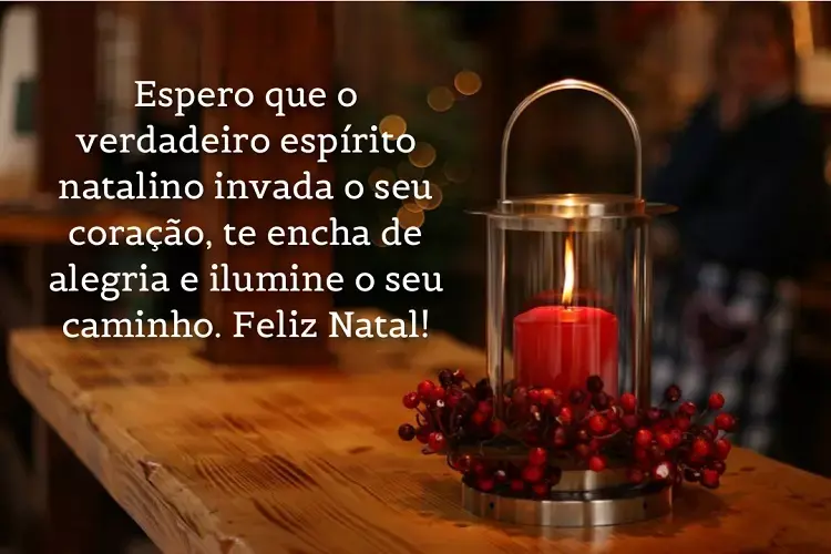 Mesa de madeira com vela acesa e frase " Espero que o verdadeiro espírito natalino invada o seu coração, te encha de alegria e ilumine o seu caminho. Feliz Natal!"