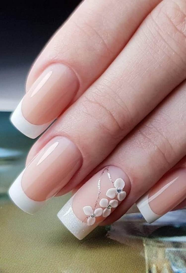 Unhas quadradas com francesinha e detalhes dourados e flores no anelar