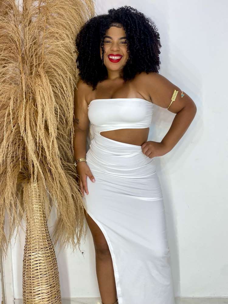 Mulher de pele negra usando vestido midi liso branco tomara que caia com um recorte na barriga