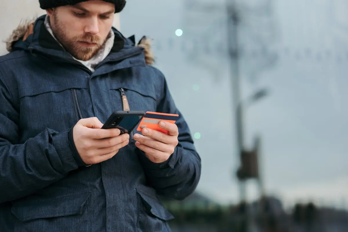 Pessoa usando celular e cartão ao mesmo tempo