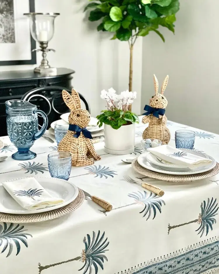 Mesa posta azul de Páscoa com coelho de Palha com laço de fita azul e detalhes em coqueiros
