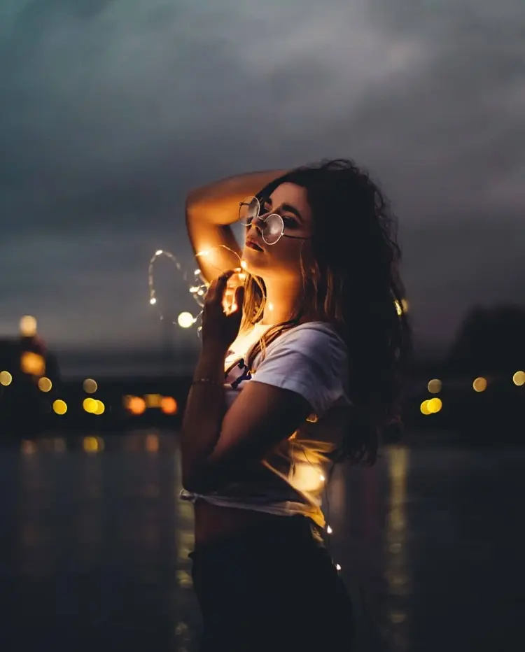 Frase para foto pensativa mulher a noite usa óculos de grau, calça preta e t-shirt branca
