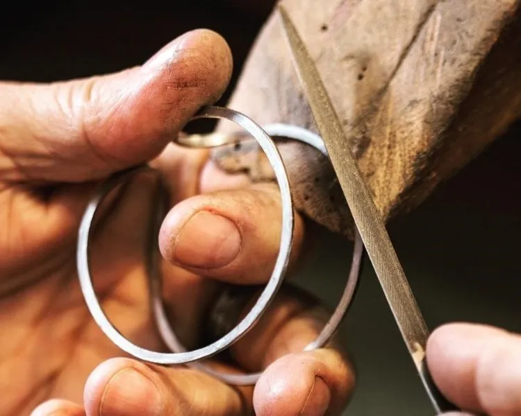 Joalheiro fazendo pulseira com metal prateado