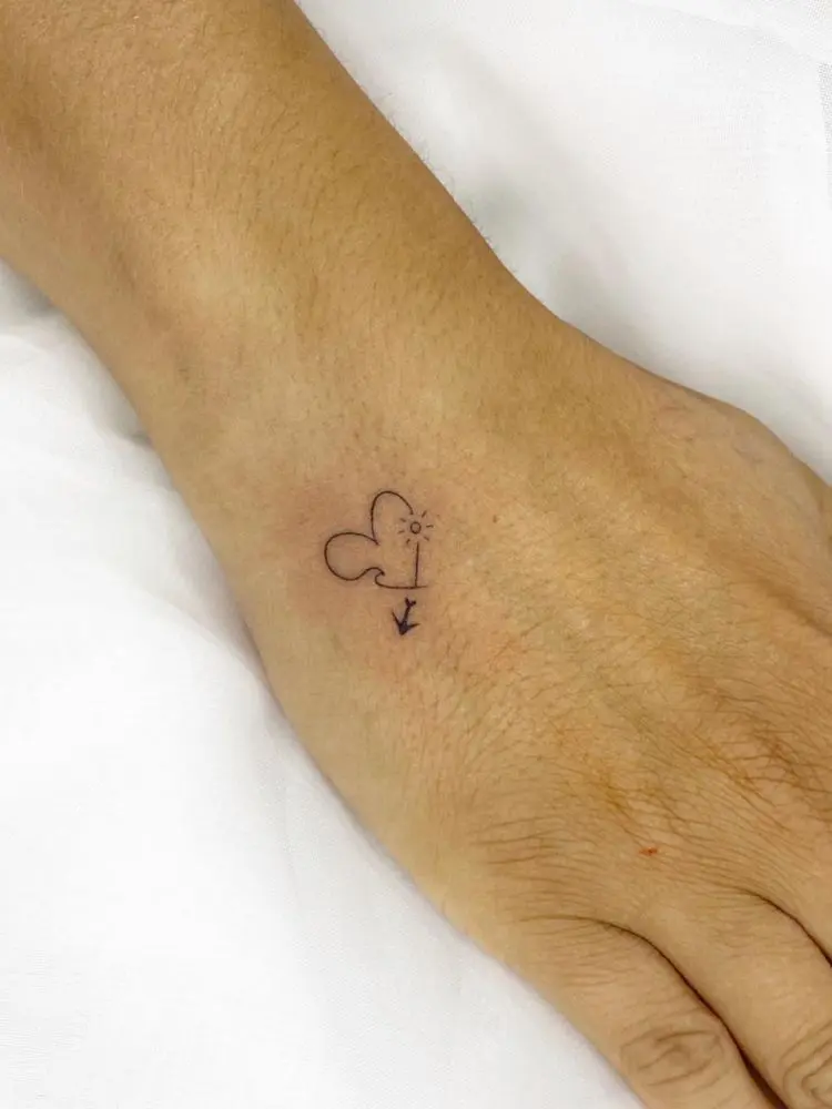 Mão com tatuagem fineline de coração, onda, sol e avião 