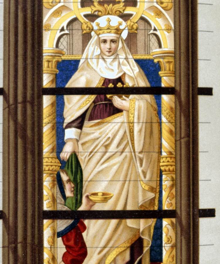 O vitral retrata Santa Isabel da Hungria em trajes reais, com uma coroa dourada. Ela está em pé, segurando um manto, enquanto uma figura ajoelhada oferece uma tigela dourada. O fundo é azul, com detalhes dourados intricados, criando um cenário majestoso. A imagem destaca a caridade e a realeza de Isabel, simbolizando sua santidade.


