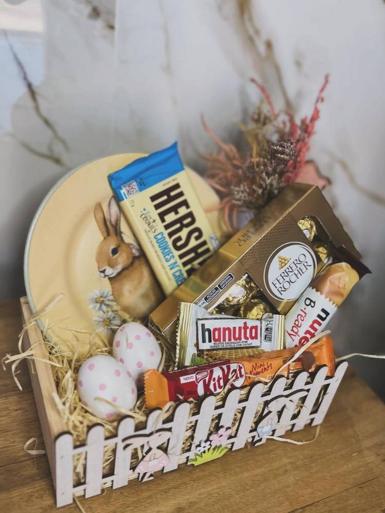 Cesta de Páscoa branca com sousplat de coelho, pequenos ovos de Páscoa, doces e flores