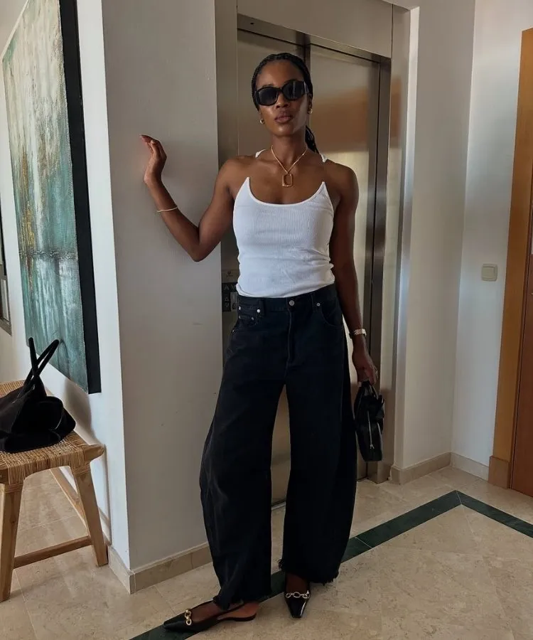 Foto de mulher negra usando regata branca e calça jeans slouchy, um dos looks para trabalhar no calor