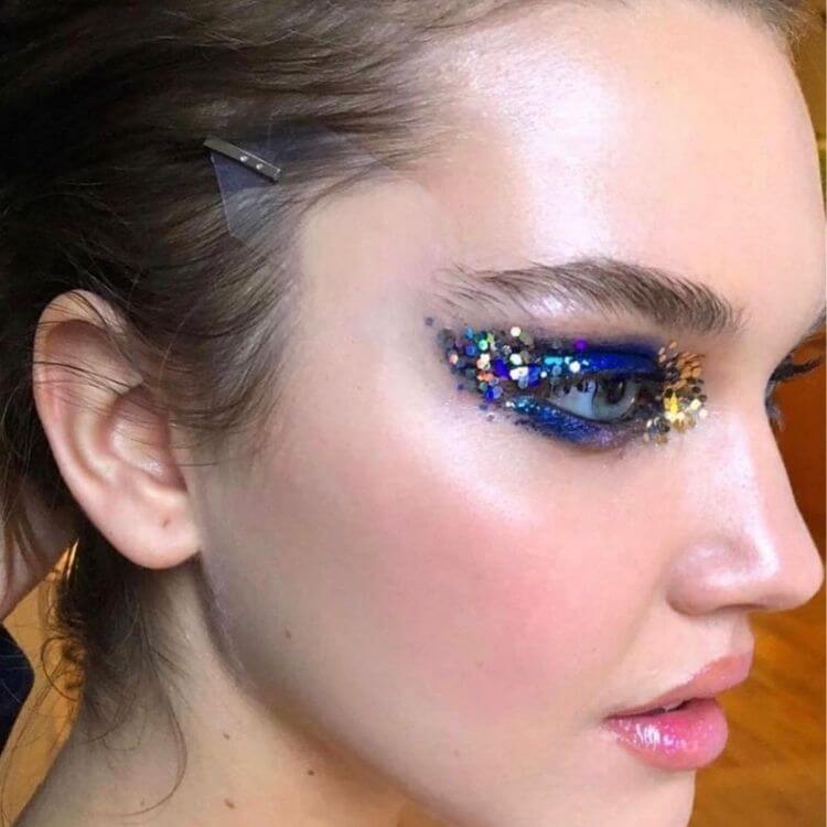 Zoom em mulher de pele clara com sombra azul e glitter flocado coloridos