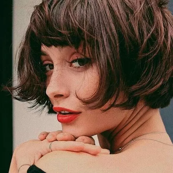 Corte cabelo curto com franja de Taylor Ashae, mulher com batom vermelho