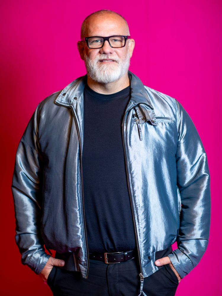 Clovis Pessoa usando blusa azul marinho, jaqueta azul cintilante e calça escura