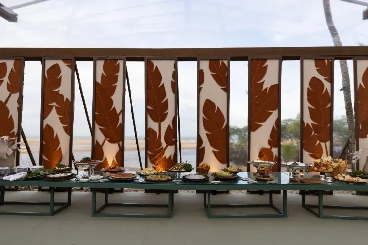 Pratos de comida em buffet de festa com decoração de folhas ao fundo