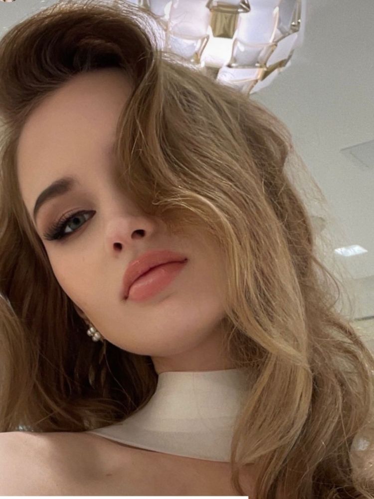 Mulher de pele clara e cabelo loiro usando maquiagem natural com olhos levemente marcados e batom rosado