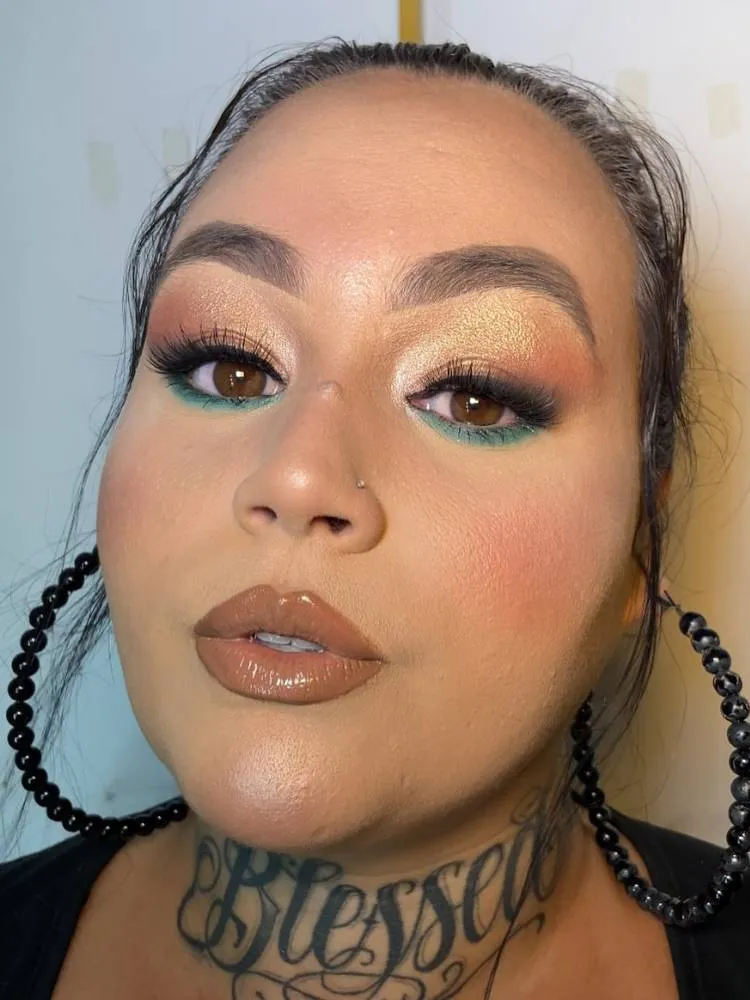 Mulher de pele branca usando maquiagem dourada nos olhos, sombra verde na marca d'água e batom nude.