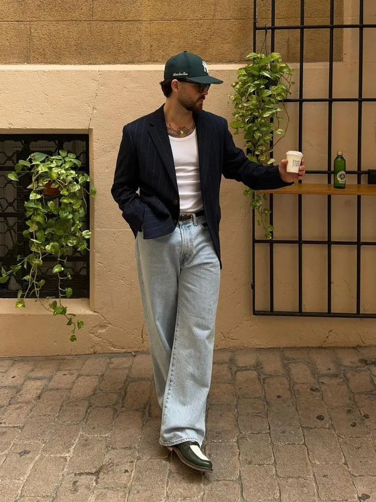 Homem de silhueta triângulo invertido usando camiseta branca, calça jeans e blazer azul marinho listrado