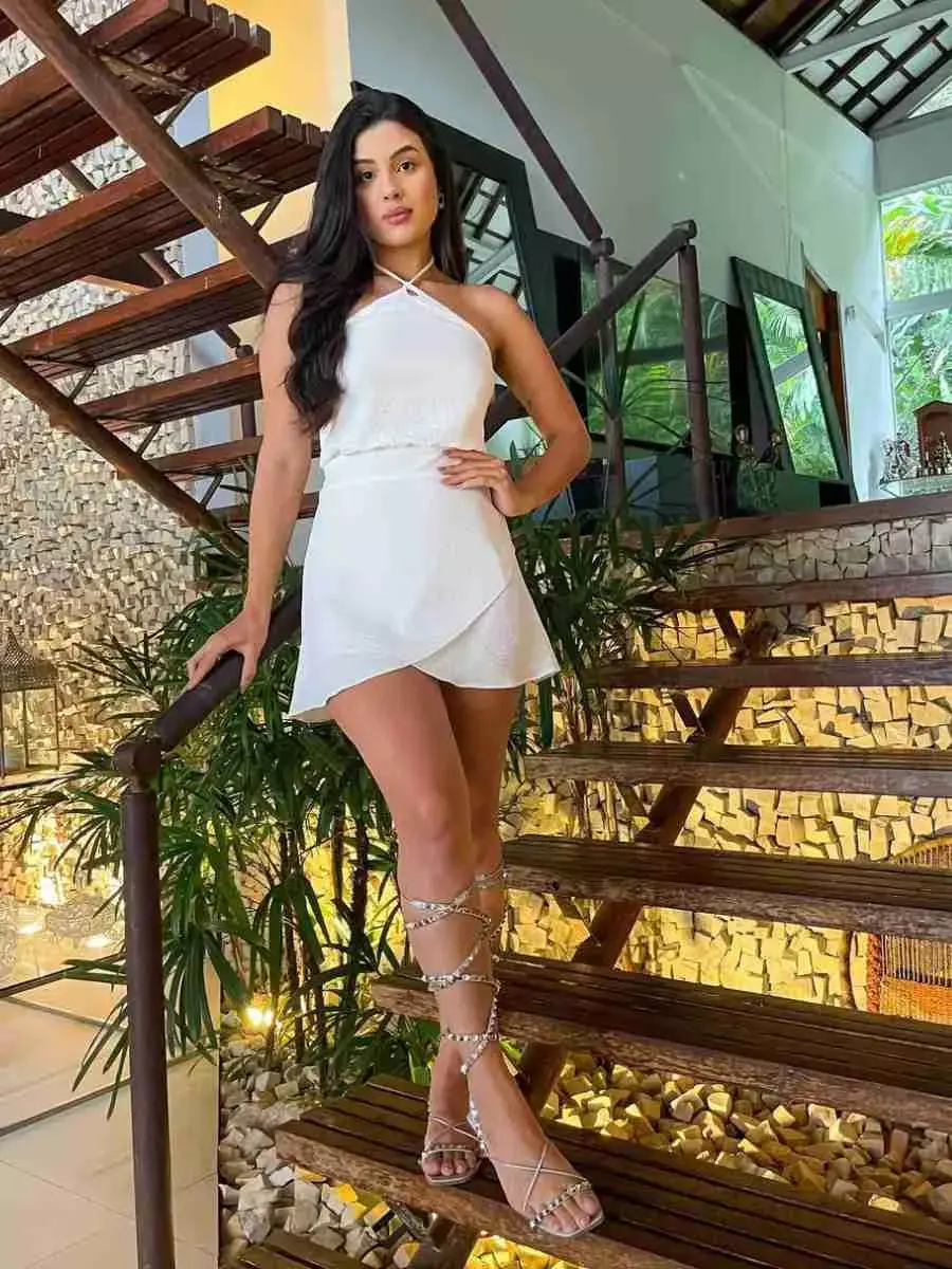 Mulher com look para o Réveillon: vestido curto branco + sandália prata.