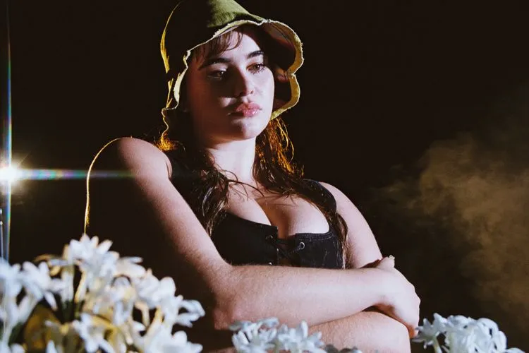 Um close-up na atriz Barbie Ferreira usando o chapéu da parceria com a Levis