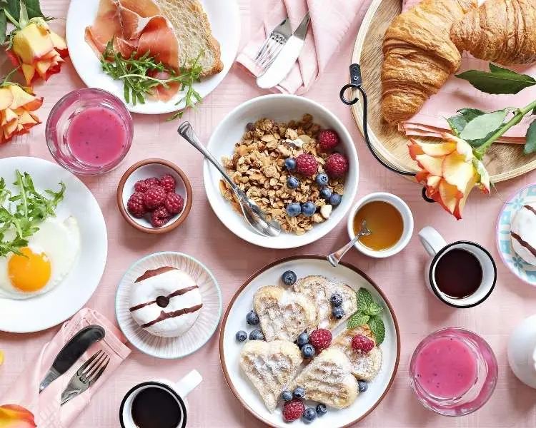 Brunch de Dia das Mães com pratos como cereais, frutas vermelhas, dunnets, sucos, ovo frito, presunto, pães