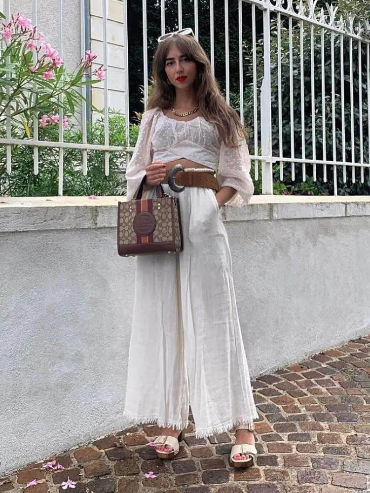Mulher usa top e pantalona brancos como sugestão de roupa para ano novo na praia