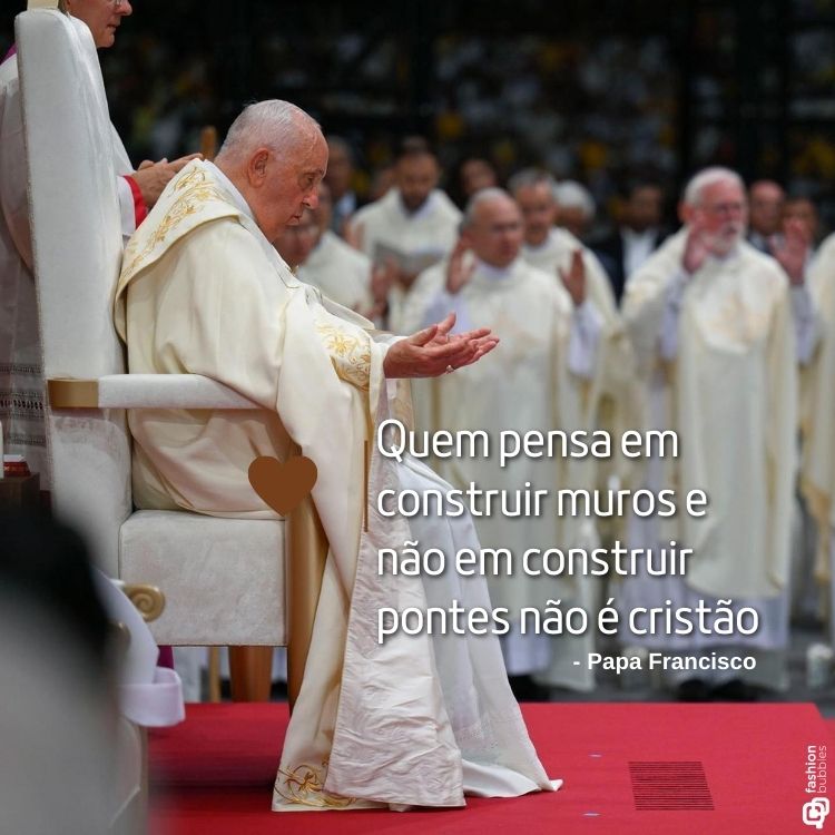 O Papa Francisco está sentado em uma cadeira, vestindo paramentos brancos, com mãos em gesto de reflexão. Ao fundo, religiosos desfocados. Em destaque, a frase: "Quem pensa em construir muros e não em construir pontes não é cristão."






