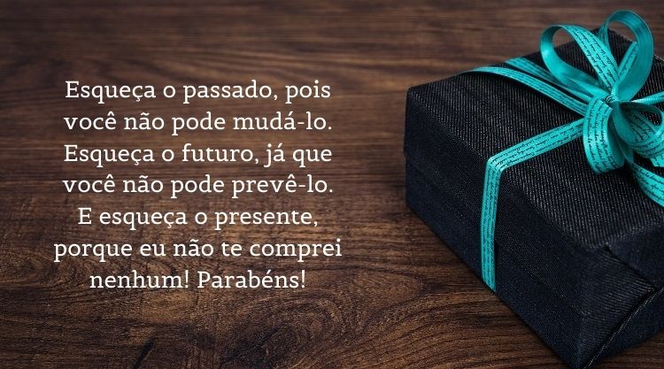 foto de presente preto em mesa de madeira com a frase " Esqueça o passado, pois você não pode mudá-lo. Esqueça o futuro, já que você não pode prevê-lo. E esqueça o presente, porque eu não te comprei nenhum! Parabéns! "