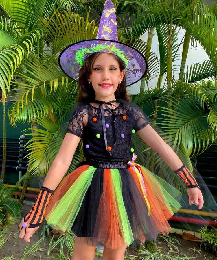 Garota fantasiada para o Halloween: Cores predominantes: .preto, lilás, abóbora e verde Usa: vestido, luvas, chapéu pontudo