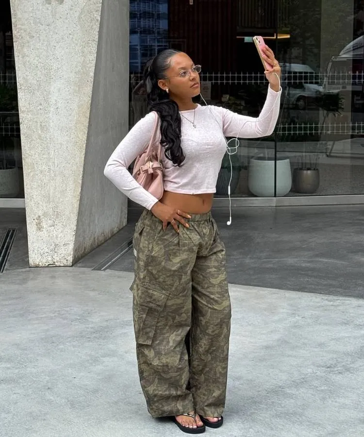 Mulher usando camiseta rosa cropped e calça com estampa camuflada