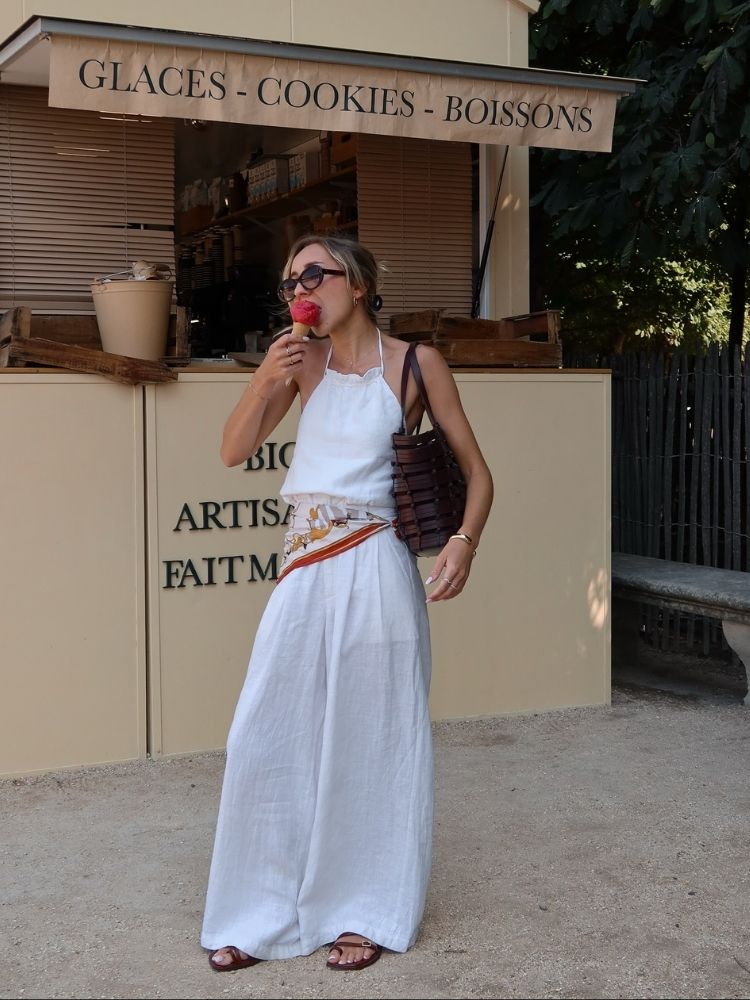 Mulher de pele clara usando blusa branca, calça branca e bandana na cintura 