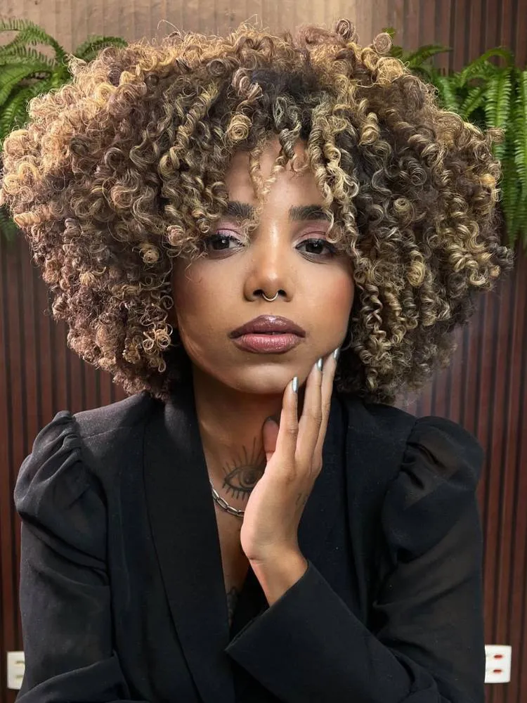 Mulher de pele negra e rosto redondo usando terno preto e black power castanho