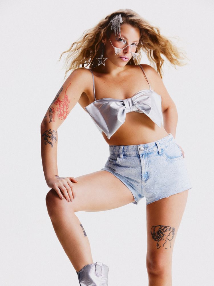 Mulher de pele clara usando cropped prta de laço e shorts jeans 