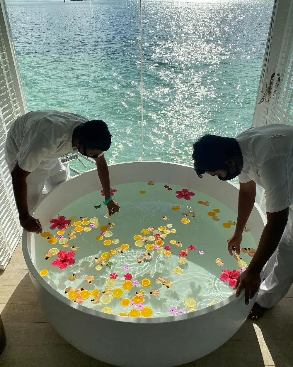 Dois homens organizam frutas na banheira de Juliana Paes.