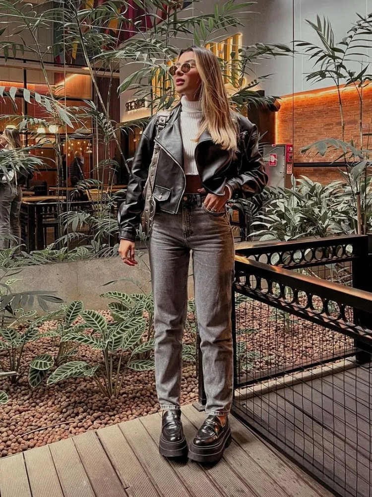 mulher usando cropped branco, jaqueta de couro, calça wide leg jeans e mocassim tratorado preto
