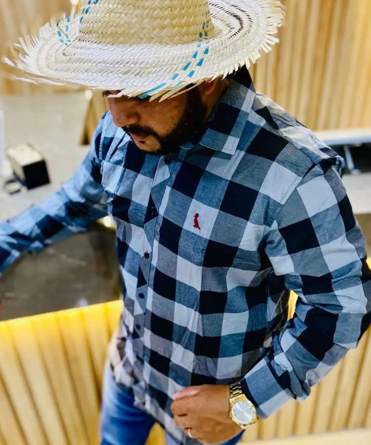 Homem com look de festa junina: camisa xadrez azul e chapéu de palha