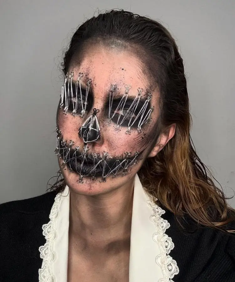 Foto de mulher usando maquiagem de Halloween com aplicação de ganchos e linha de costura