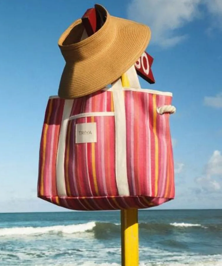 Bolsa de praia listrada com viseira de palha em cima