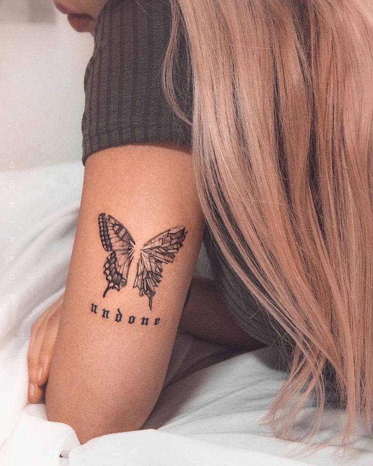 Tatuagem de borboleta no braço sendo uma das asas de vidro e palavra "undone"