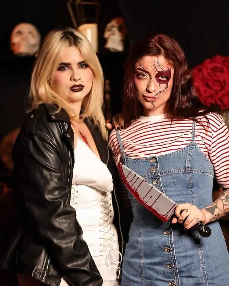 Duas mulheres fantasiadas: uma loira de freddy kruegger com batom escuro e outra de Chucky, com rosto simulando machucados