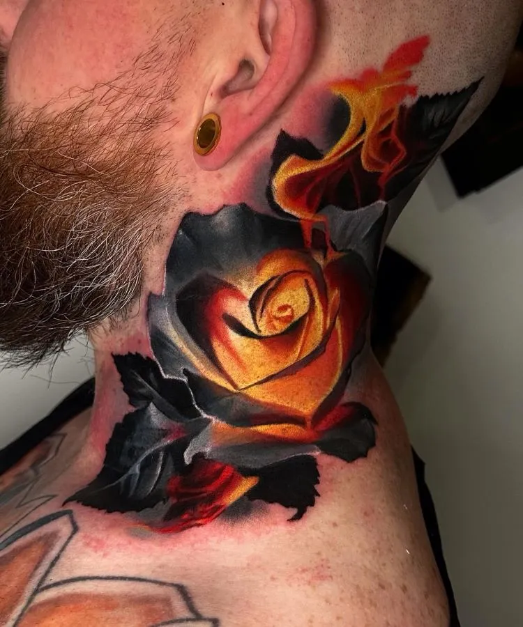 A imagem mostra uma pessoa de perfil com barba ruiva e alargador dourado na orelha. Ela tem uma tatuagem no pescoço de uma rosa vibrante em tons de amarelo e laranja, com folhas e detalhes em preto. A tatuagem cobre a lateral do pescoço até o ombro.


