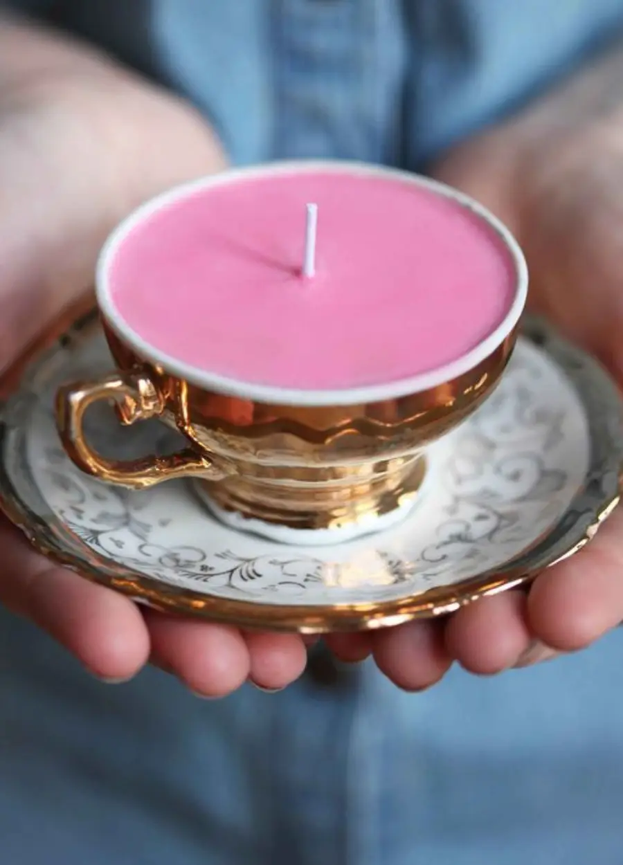 Vela curativa rosa na xícara de chá dourada