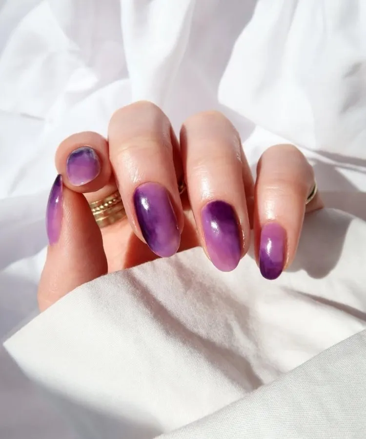 Foto de unhas pintadas com esmalte roxo ametista, uma das tendências de unhas para 2026