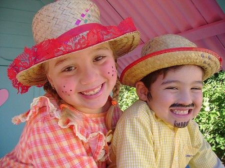 Menina e menino com make de festa junina e chapéus de palha