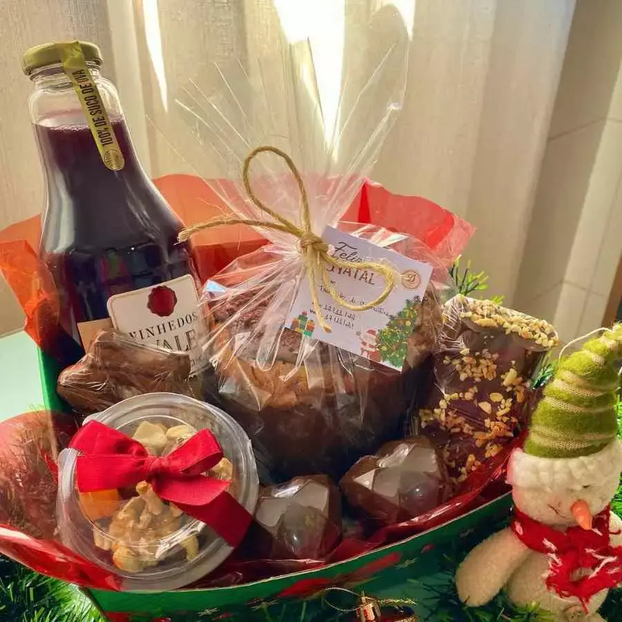 Foto de cesta com panetone, suco de uva e doces.