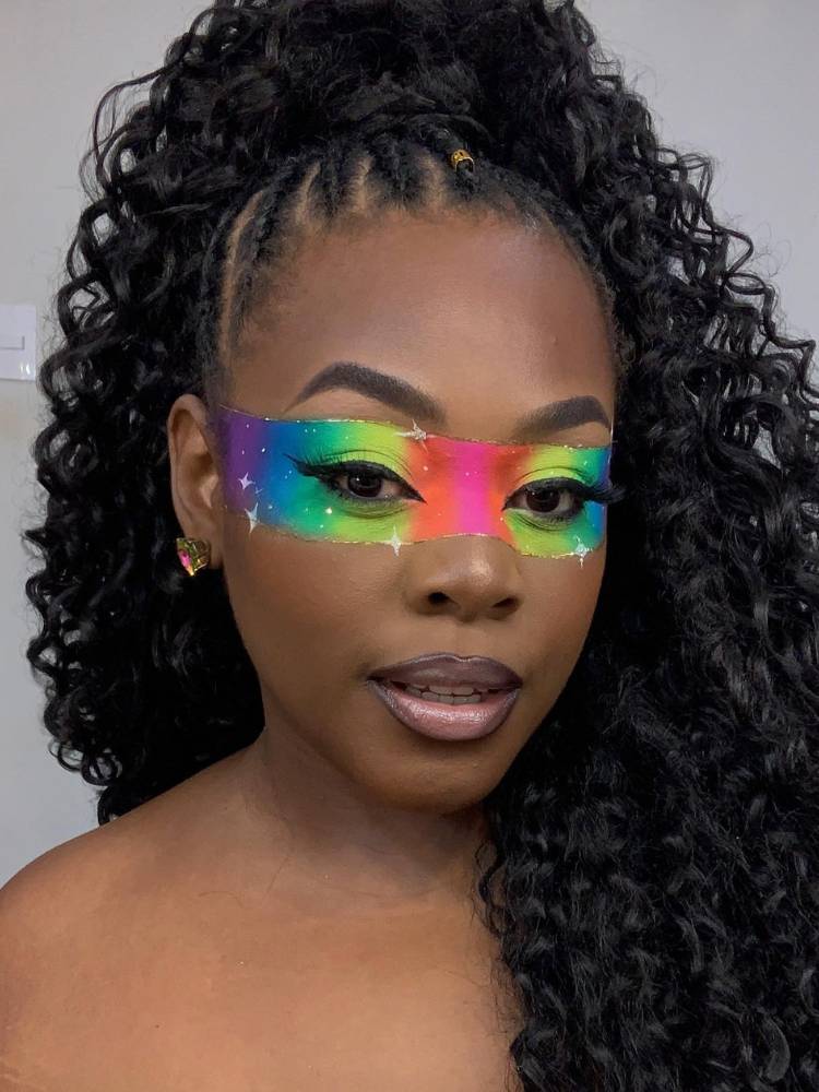 Mulher de pele negra com maquiagem colorida na faixa dos olhos. 