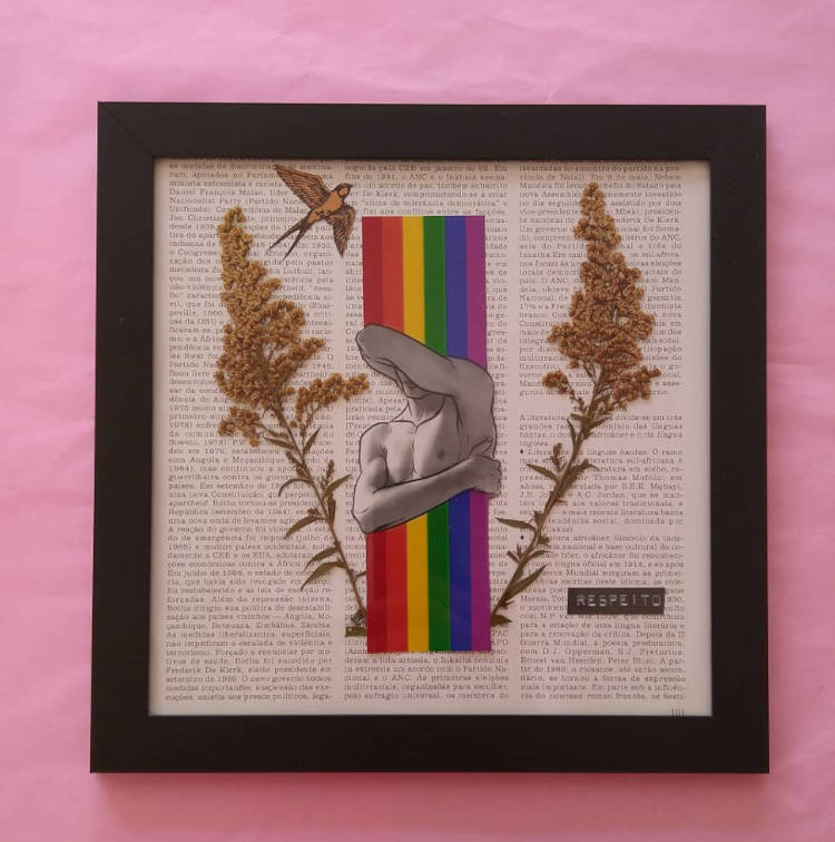 Quadro de moldura preta com texto atrás, detalhes nas cores da bandeira LGBT, flores e estátua, pregado em parede rosa