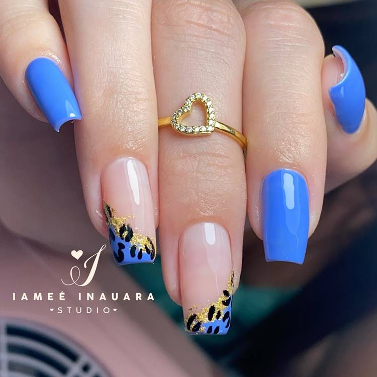 Unhas decoradas em tons de azul com oncinha e glitter dourado